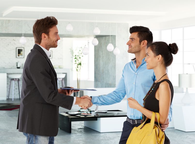 Couple shaking hands with realtor in new home