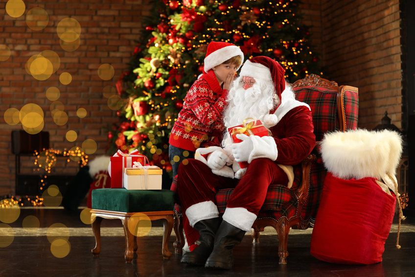 Santa Claus and little boy near Christmas tree indoors