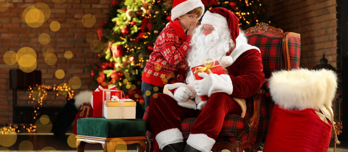 Santa Claus and little boy near Christmas tree indoors